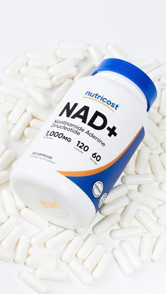 A high-resolution top-down product shot of an NAD+ supplement bottle surrounded by loose capsules on a clean white surface.